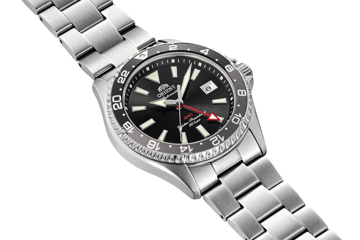 Angled view of Orient RA-BC0001B Kamsu GMT watch with a black sunburst dial, black-and-gray 24-hour bezel, date window, and stainless steel bracelet