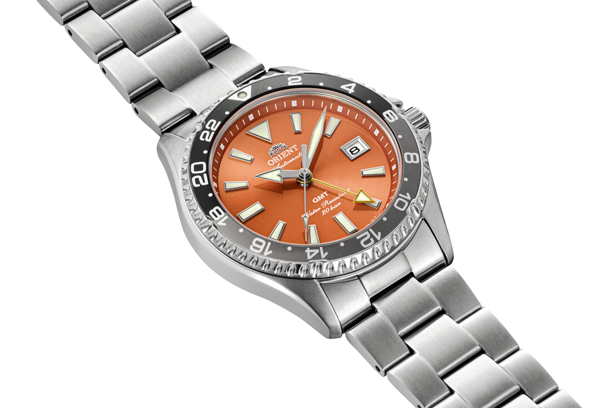 Angled view of the Orient RA-BC0004Y Kamasu GMT watch with a orange dial, black-and-gray 24-hour bezel, and stainless steel case and bracelet.