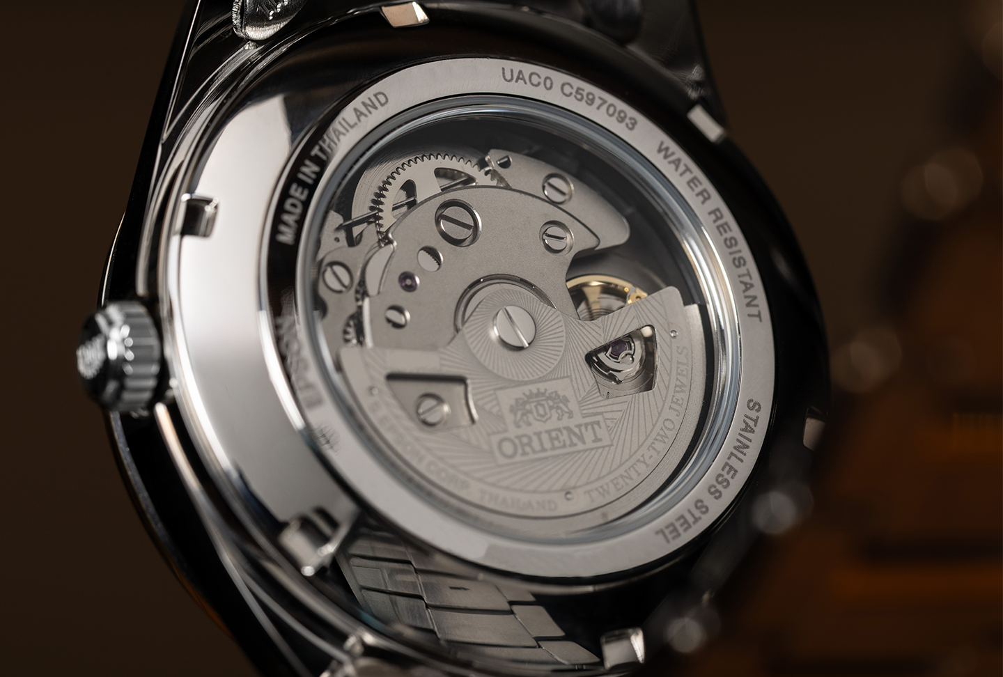 Close-up of a mechanical watch's back, showcasing intricate gears and components through a transparent case. The steel surface reflects ambient light, exuding precision and craftsmanship.